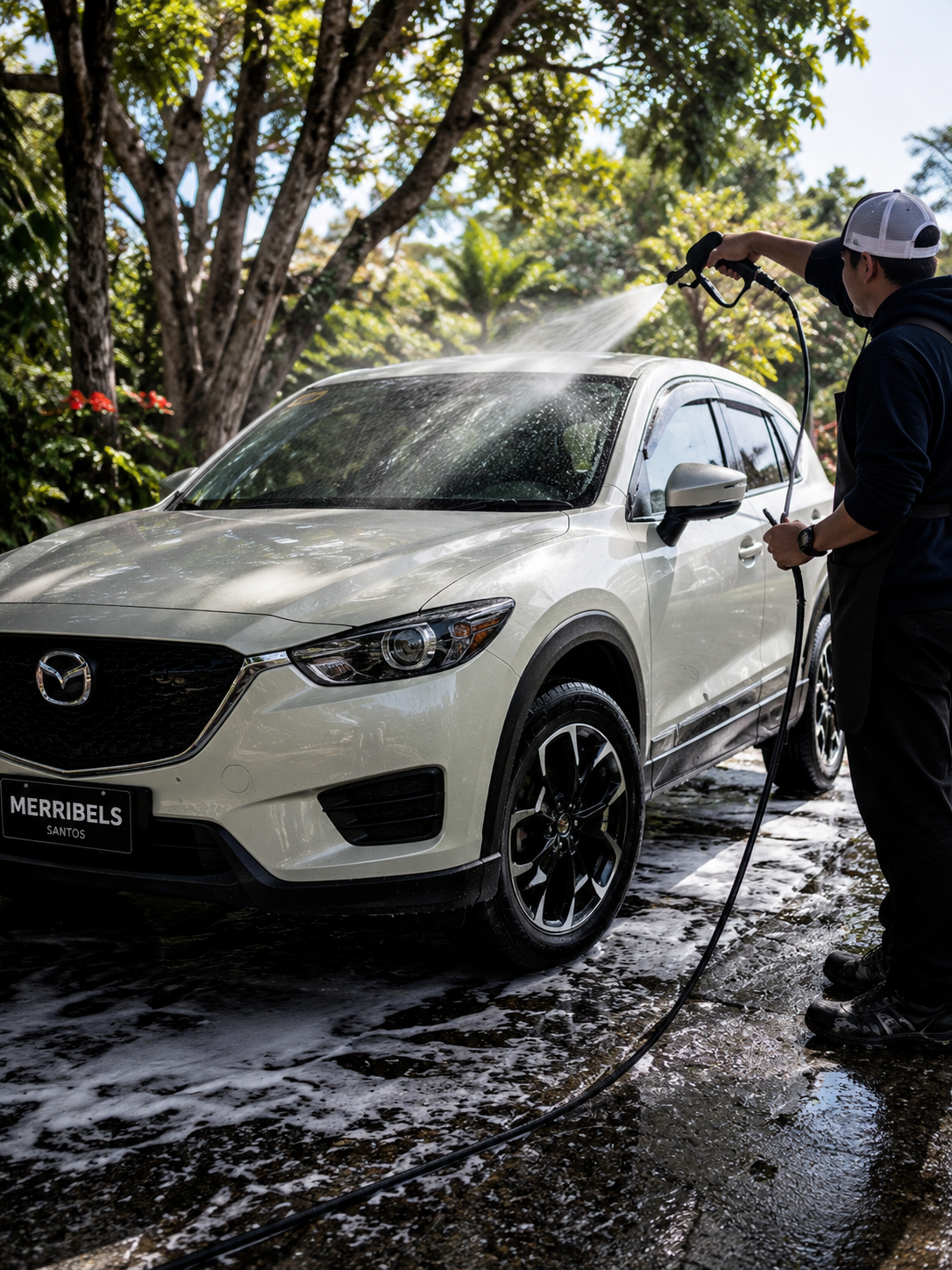 Detailer rinsing a white vehicle outdoors